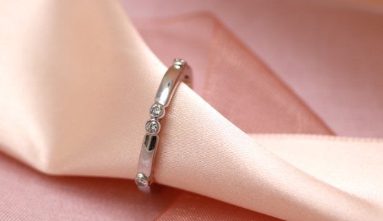 White gold wedding ring, set with diamonds, set in a closed setting, placed in an irregular manner around the finger. Jewellery made in France, by Annette Girardon, in Paris.