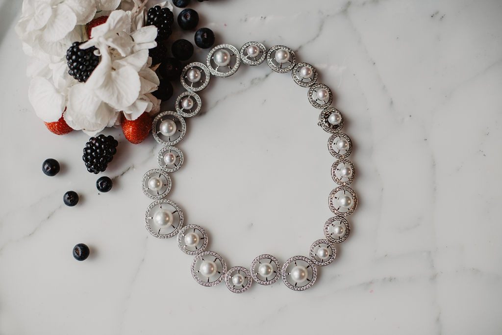 Collier formé de cercles de différentes taille enor blanc, sertis de diamant avec une perle au milieu.