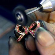Le pendentif joaillerie "petit nœud" se trouve ici entre les mains de la polisseuse lui donnera tout son éclat. En or blanc, il est serti de saphirs roses et porté sur un collier en jaspe brun.