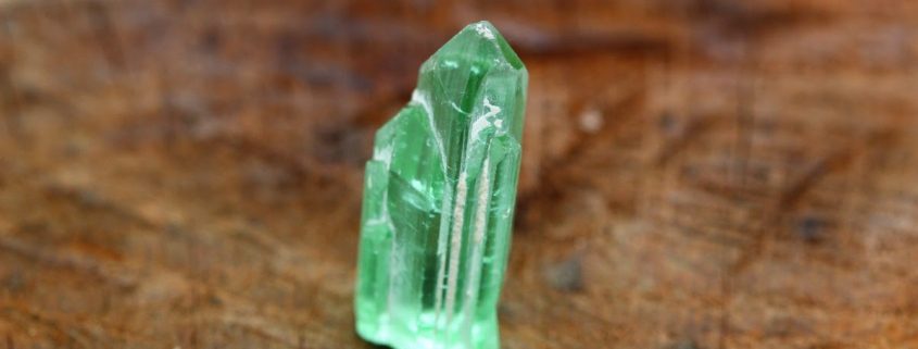 Lagoon green rough tourmaline on a wooden background.