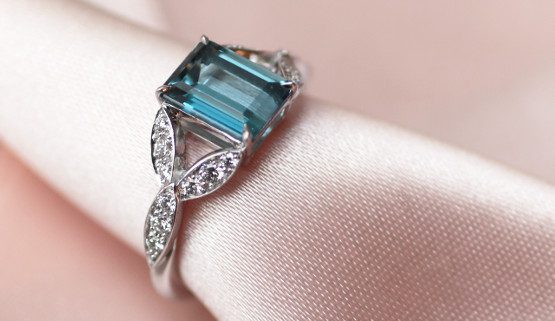 This engagement ring for women features a rectangle aquamarine of the Santa maria africana variety. The ring is made of palladium white gold and is set with diamonds on elements evoking leaves.