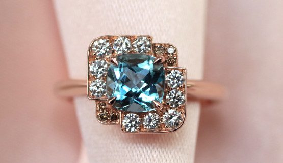 handgearbeiteter verlobungsring Dieser originelle roségoldene Verlobungsring für die Frau stellt ein Quadrat dar, mit einem Aquamarin im Antik Schliff in der Mitte, umgeben von weißen und braunen Diamanten.