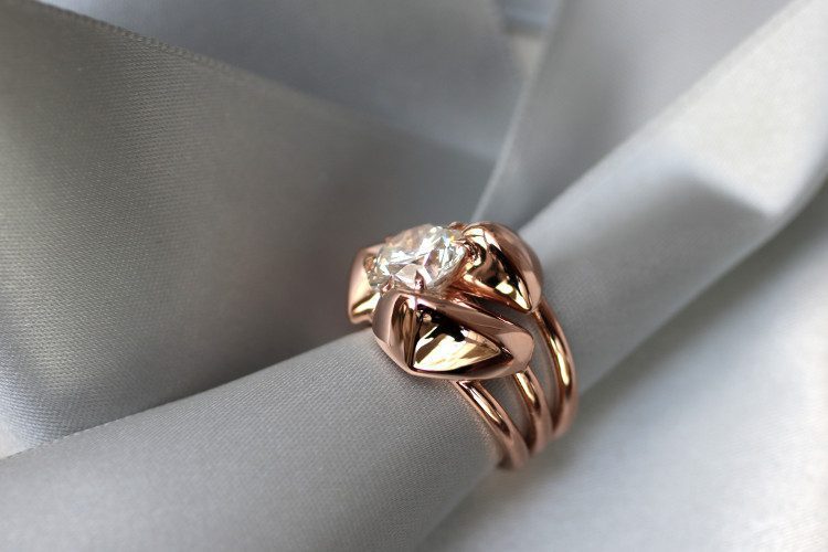 Une bague femme en or rose, dans un style rock, avec trois anneaux et trois pépites d'or, sertie d'un diamant de trois carat. Ce diamant a trouvé sa place entre les pépites.