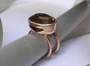 Bague de taille importante, créée sur-mesure pour une pierre client Cette bague est une création sur-mesure. Une grosse citrine verte ovale a été sertie dans une coupelle en or rouge, allégée par une ouverture latérale. Le corps de bague est fait par deux anneaux parallèles et écartés.