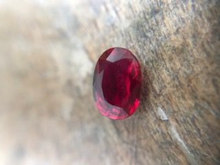 Rubis pierre symbole Un très joli rubis oval plutôt pur sur un établi en bois pour illustrer un article traitant de la signification des pierres.