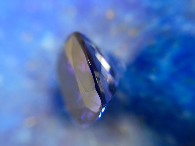 signification des pierres Une tanzanite en vue de profil contre du lapis lazuli, flou au fond, comme introduction d'un article traitant de la signification des pierres.