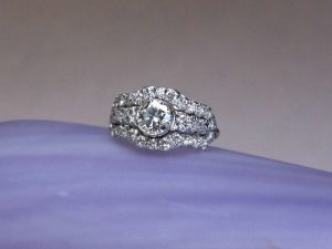 bague-style-art-deco- Bague de fiançailles faite sur-mesure en or blanc sertie de diamants, dans le style Art Déco. Un bandeau angulaire, en plusieurs parties, plus large au centre où se trouve un diamant de 6 mm de diamètre , s'arrète à la hauteur mis doigts.