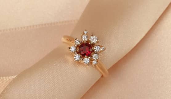 bague de fiançailles rubis entourée de motifs diamants asymétriques Sur cette bague de fiançailles rubis en or rose, le rubis rond au centre est entouré de motifs en diamants variés et assymétrique. Il y a des formes inspirées de feuilles et des diamants de tailles variables.