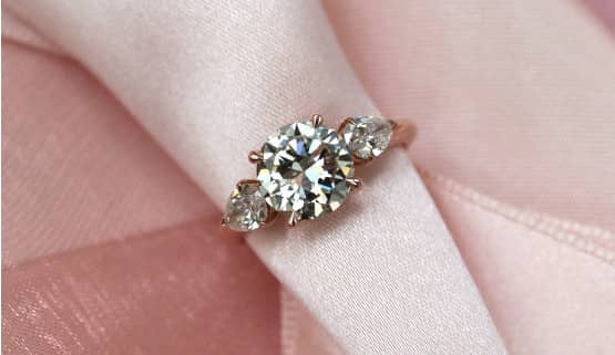Bague de fiançailles classique sur-mesure Bague de fiançailles sur-mesure pour un diamant de deux carats, accompagné de deux diamants poire sur or rose, faite à Paris, par Annette Girardon.