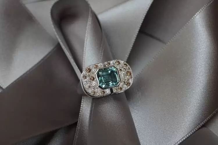 Cette bague de caractère, façonnée dans le style art déco moderne, en or blanc, sertie d'une aiguemarine et d'un pavage de diamants bruns et blancs vient de la joaillière Annette Girardon.