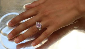 Une bague pavée de saphirs violets, d'un design aérien est présentée sur une main, de fabrication joaillerie paris.