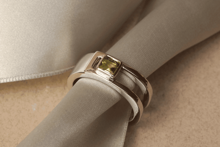Bague homme pierre verte Une bague homme en platine qui forme un bandeau partiellement ouvert, est sertie d'une pierre verte, un péridot. Les bijoux homme avec des pierres précieuses sont tendance.