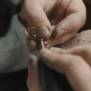 Un bijou est entre les mains de la joaillière pour être pré-poli, dans un atelier de joaillerie à Paris. Cette image illustre la fabrication sur-mesure.