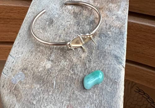 Un bracelet en or avec un cabochon en jade à côté, taillé sur-mesure à Paris, prêt pour le sertissage