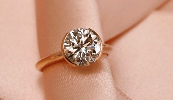 solitaire-bague-fiancaille Un diamant de plus de 2 carats est monté en solitaire de façon très contemporaine. Sur un tiers de sa circonférence, un filet d'or serti la pierre de chaque côté.