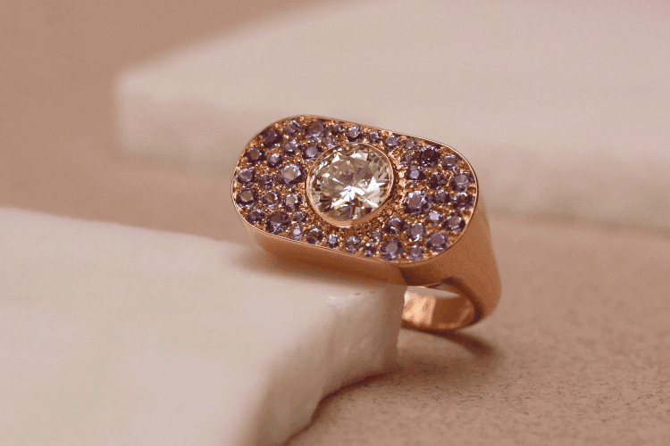 Cette bague sur-mesure à été créée pour le diamant qui se trouve sur un plateau rectangulaire aux bords arrondis, pavé de saphirs parmes..