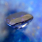 Ein Tansanit Stein ist im Profil vor einem Lapislazuli abgebildet, welcher in unscharfer Form den Hintergrund füllt.