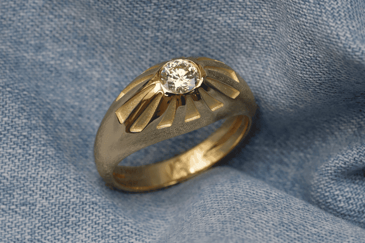 herrenringe-diamant Der konisch geformte Herrenring aus Gelbgold ist mit einem Diamanten von 0,57 Karat besetzt. Der obere Teil des Rings ist mit Gravuren verziert. Diese maßgeschneiderte Kreation wurde von Annette Girardon in Paris angefertigt.