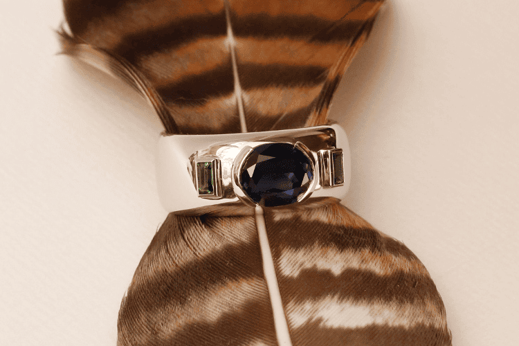 mens-designer-fine-jewellery The oval sapphire, set in this platinum band ring for men, was brought to Paris by a customer from far away. It is flanked by two green tsavorite baguettes.